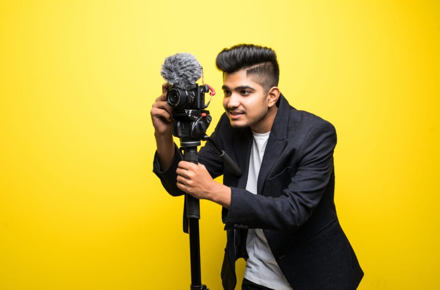 Indian professional cameraman covering on event with a video on yellow background